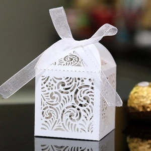 Elegant white laser-cut wedding favor box with floral patterns and a soft chiffon ribbon