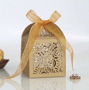 Elegant gold laser-cut wedding favor box with floral patterns and a matching ribbon bow