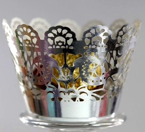 Macro detail of laser-cut silver hollow cupcake wrapper with intricate floral patterns