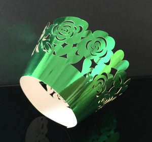 Detail of laser-cut rose pattern on metallic green muffin cupcake wrapper with reflection