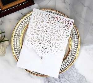 Detailed laser-cut rose pattern on white wedding invitation with sparkling rhinestone