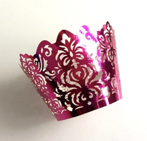 Magenta laser-cut cupcake wrappers with intricate floral patterns and metallic finish