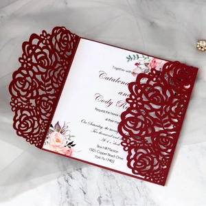 Elegant burgundy laser-cut rose wedding invitation card on white marble background