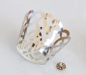Macro detail of laser-cut heart pattern cupcake wrapper with silver finish and rhinestone
