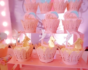 Detailed view of pink laser-cut cupcake wrappers and toppers on a tiered stand