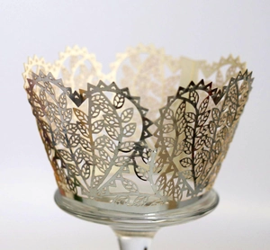 Macro detail of laser-cut cupcake wrapper with champagne gold leaf and floral patterns