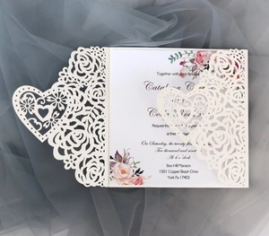 Detail lasergeschnittener Herz- und Rosenmuster auf einer weißen Hochzeitseinladung