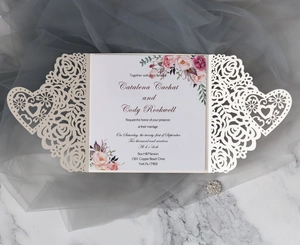 Detail des lasergeschnittenen Rosen- und Herzmusters auf einer weißen Hochzeitseinladung