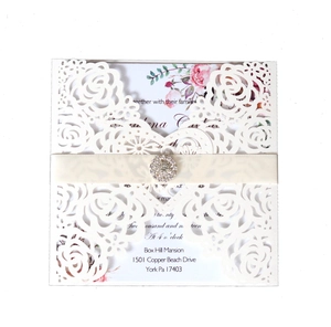 Detail der lasergeschnittenen Hochzeitseinladung mit floralem Muster und Strass-Schleife