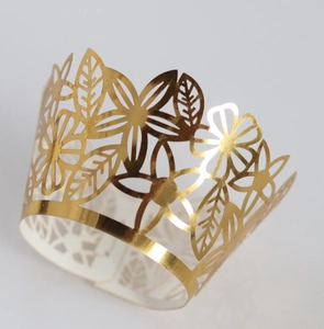 Detail view of gold laser-cut lace cupcake wrappers with intricate floral patterns