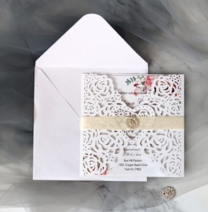 Detail der lasergeschnittenen Einladung mit Blumenkarte, weißem Band und Strass-Schnalle