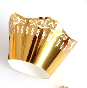 Close-up of laser-cut lace cupcake wrapper with metallic gold finish and floral patterns