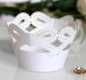 Macro shot of laser-cut white lace paper cupcake wrapper with floral and polka dot details