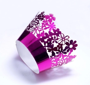 Detail of laser-cut flower patterns on purple metallic cupcake wrappers for party decor