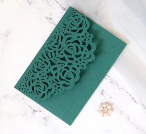 Detail of dark green laser cut invitation cover with intricate floral rose patterns