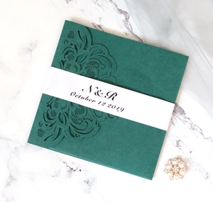 Detailed laser-cut dark green wedding invitation with elegant white belly band decor