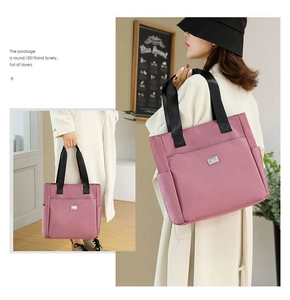 Detail view of pink large capacity Oxford tote bag with black straps and side pocket