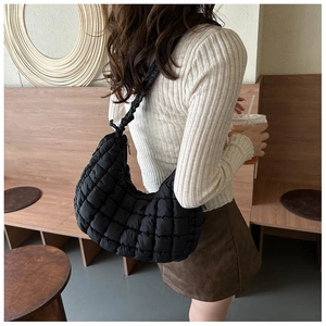 Detail of black quilted puffer shoulder bag in soft nylon with elegant grid pattern texture