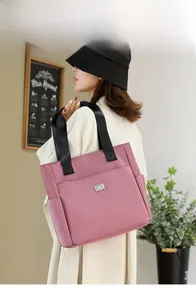 Detail of a large pink Oxford tote bag with multiple pockets and black woven straps