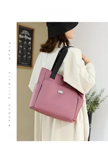 Detailed view of large pink nylon tote bag with side pockets shown on a female model