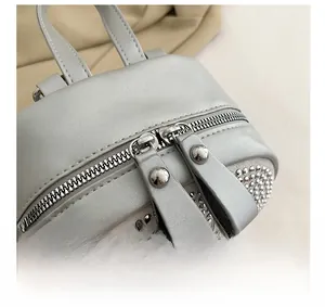 Dettaglio di un mini zaino grigio argento con strass scintillanti e cerniere in metallo