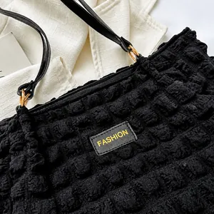 Close-up of black bubble textured fabric with fashion logo label and gold metal rings