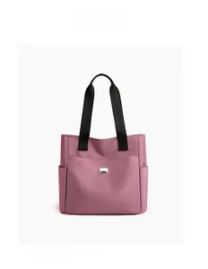Detail view of pink oxford tote bag with sturdy black nylon handles and metal logo