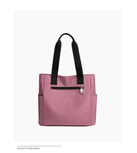 Detail view of pink nylon tote bag showing front zipper pocket and black handles
