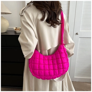 Detail view of pink quilted cloud shoulder bag texture and stitching on a female model