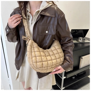 Beige quilted crescent shoulder bag showing its puffy texture on a female model