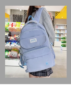 Detail of light blue waterproof nylon backpack with multiple pockets and cute plush charms