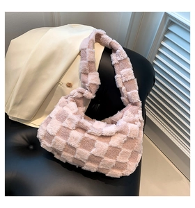 Detail of soft pink and white checkered plush shoulder bag on a black leather bench