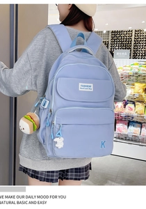 Detail of light blue waterproof backpack with plush charms and functional pockets