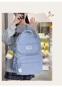 Detail of light blue waterproof nylon backpack with fashion labels and plush burger charm