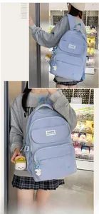Detail of light blue nylon backpack with fashion labels and cute cartoon pendants