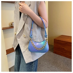 Detail der irisierenden lila Sichel-Tasche mit Goldkette und gewebtem Riemen am Modell