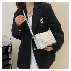 Macro shot of white crossbody bag featuring stylish waffle texture and decorative chunky chain