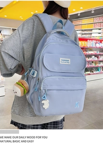 Detail of light blue waterproof backpack featuring cute charms and multi-pocket design