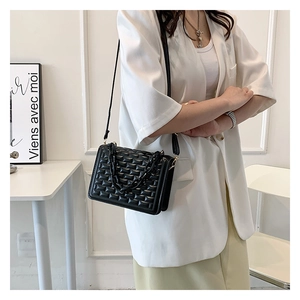 Detail of black crossbody bag with quilted texture and thick acrylic chain decoration