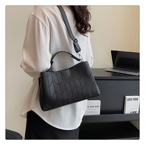 Detail of black quilted leather handbag with geometric V-stitching and adjustable strap