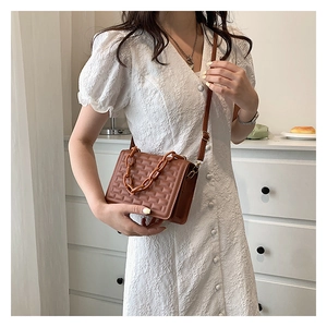 Brown quilted crossbody bag featuring textured square patterns and chunky resin chain strap