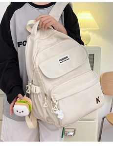 Detail of cream canvas backpack with fashion embroidery and decorative cute charms