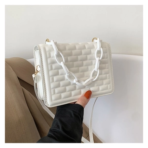 Detail of white quilted crossbody bag featuring brick-pattern texture and acrylic chain