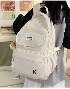 Detailed view of the multi-pocket cream-white nylon backpack with adjustable buckles