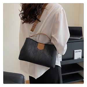Detail of black quilted leather handbag with V-shaped stitching and brown shoulder strap