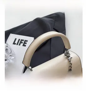 Dettaglio della borsa beige quadrata con manico tondo spesso e catena in metallo argento