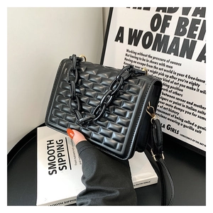 Detailed close-up of the black quilted crossbody bag featuring a chunky chain handle
