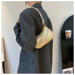 Irisierende Handtasche mit Schlangenmuster und goldener Kette getragen zu grauem Blazer