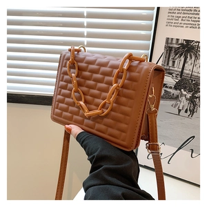 Detail of brown square crossbody bag featuring waffle texture and acrylic chain handle
