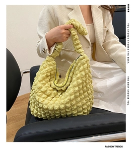 Detail of soft yellow cloud shoulder bag with popcorn texture and matching pleated strap